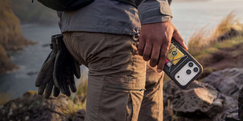 man hiking and holding an OtterBox Sole Series Pack phone case on iPhone 17 Pro Max