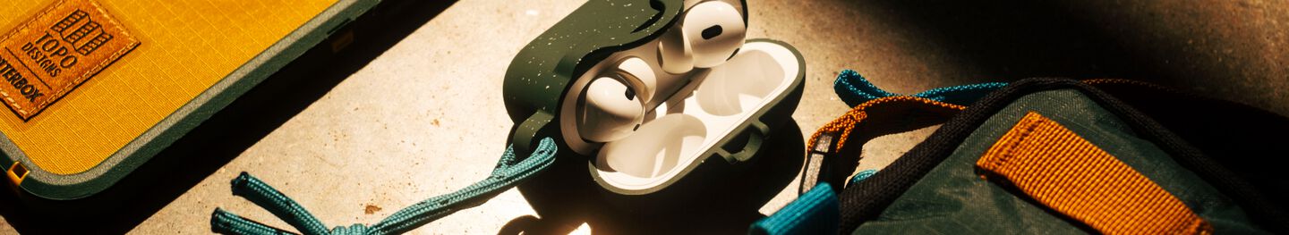 OtterBox x Topo Designs branded AirPods case, shoulder bag and iPhone 17 Pro Max phone case on a desk