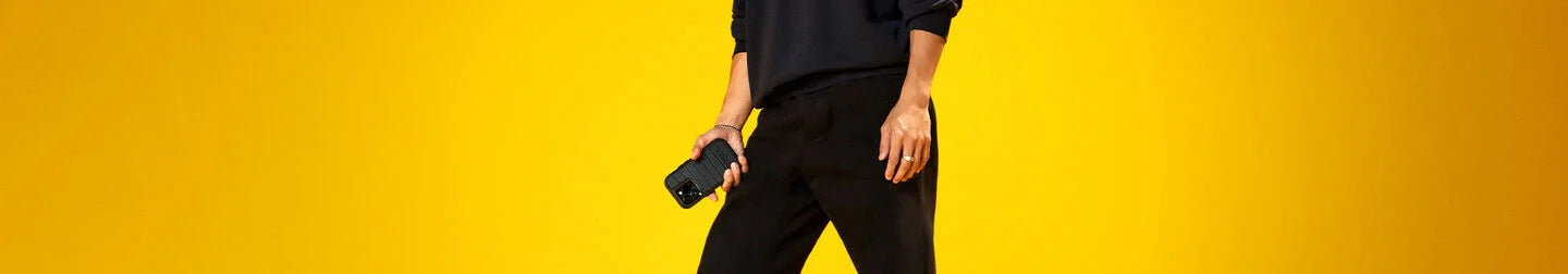 Person holding black OtterBox iPhone case on a golden yellow background