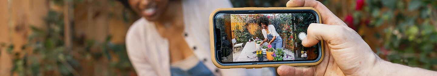 Woman taking a photo on her iPhone with OtterBox protective phone case and OtterBox Glass screen protector