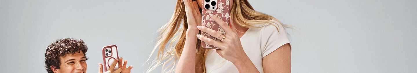 Man and woman taking pictures on their iPhone 16 Pro Max phones in OtterBox Defender Series phone cases