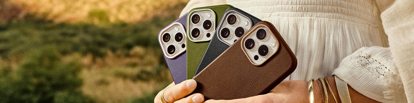 Woman holding a variety of colorful OtterBox Symmetry Series Cactus Leather iPhone 16 Pro cases on a desert background