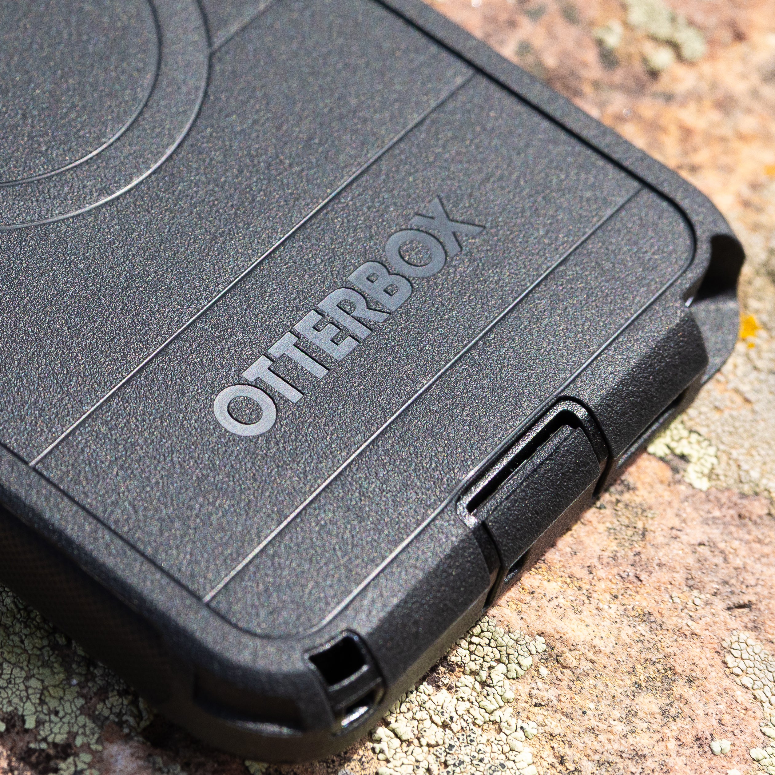 Close up of black OtterBox case and port covers on a textured surface