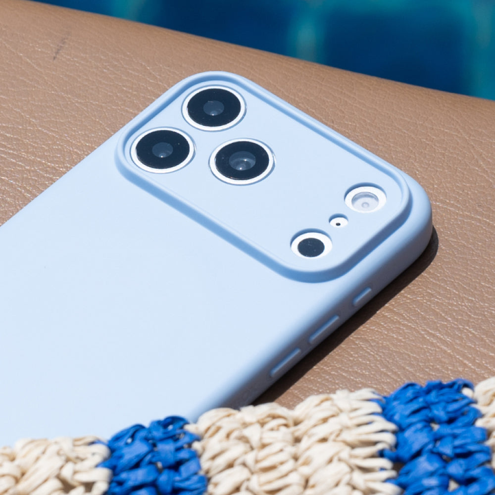 A light blue protective phone case fitted on a smartphone, shown close-up on a brown textured surface with a blue and cream woven mat in the foreground.