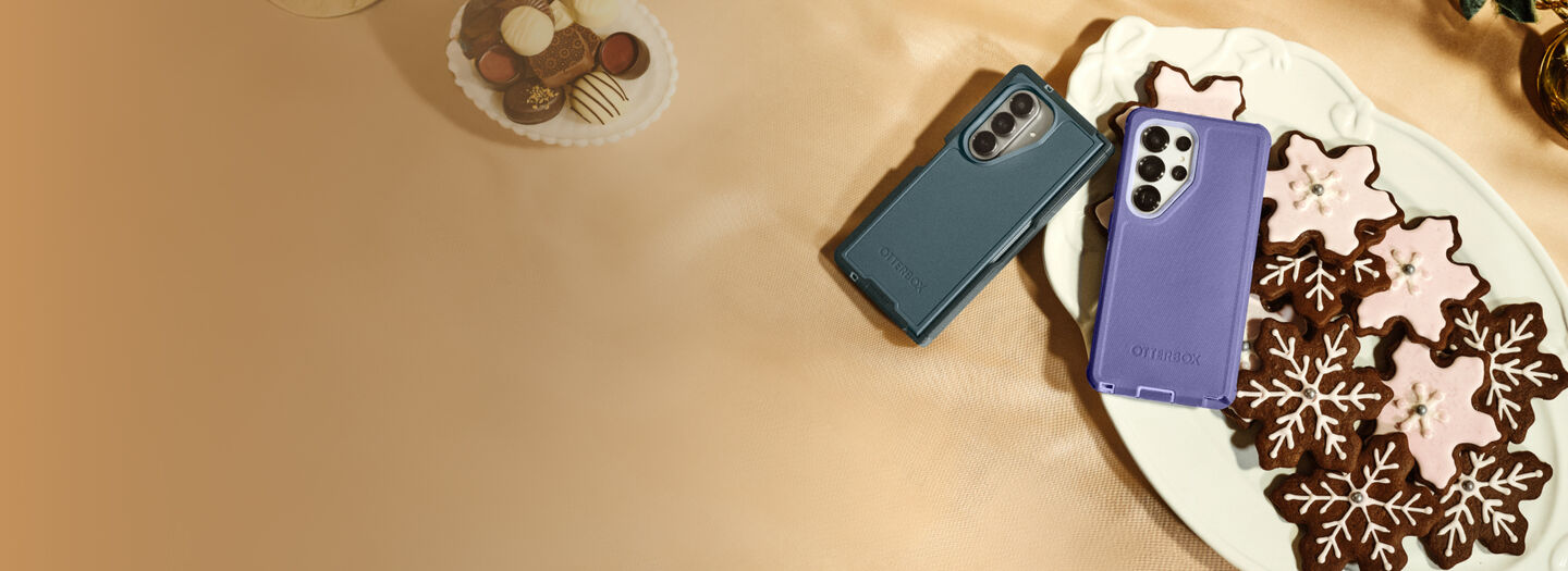 Two phone cases, one blue and one purple, on a plate with cookies.