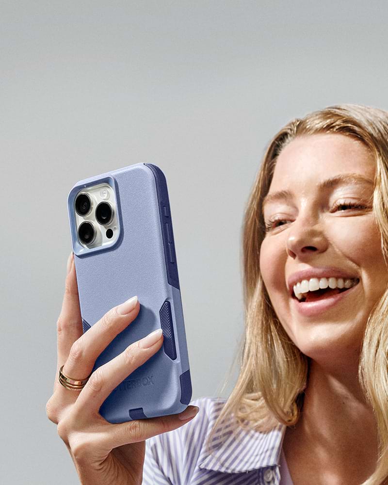 woman smiling while holding iphone 16 a blue otterbox commuter series case