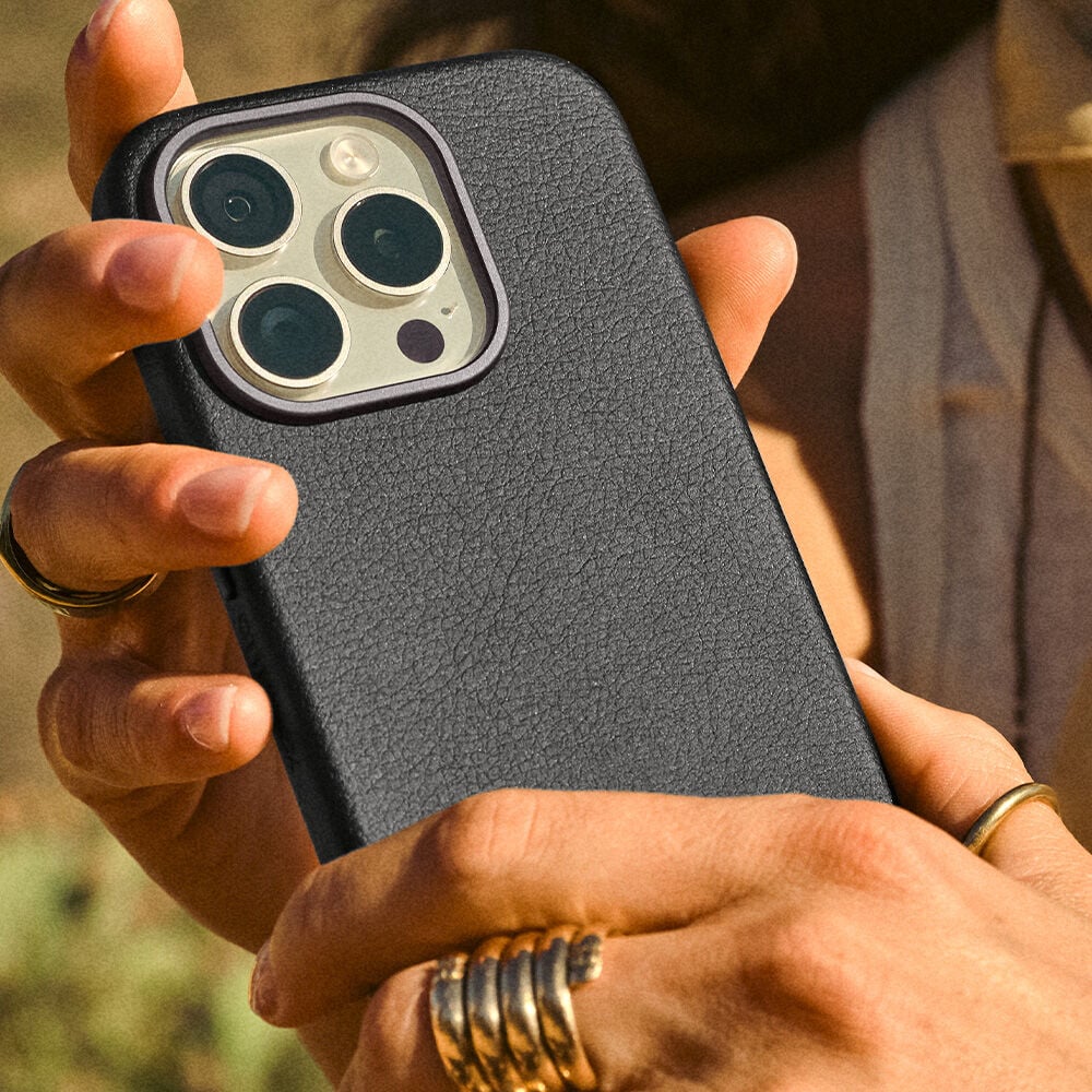 Person holding a phone with a cactus leather black case outdoors