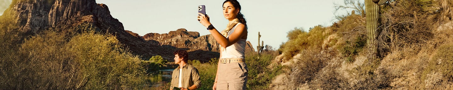 Two people in a desert landscape with cacti and rocky formations.