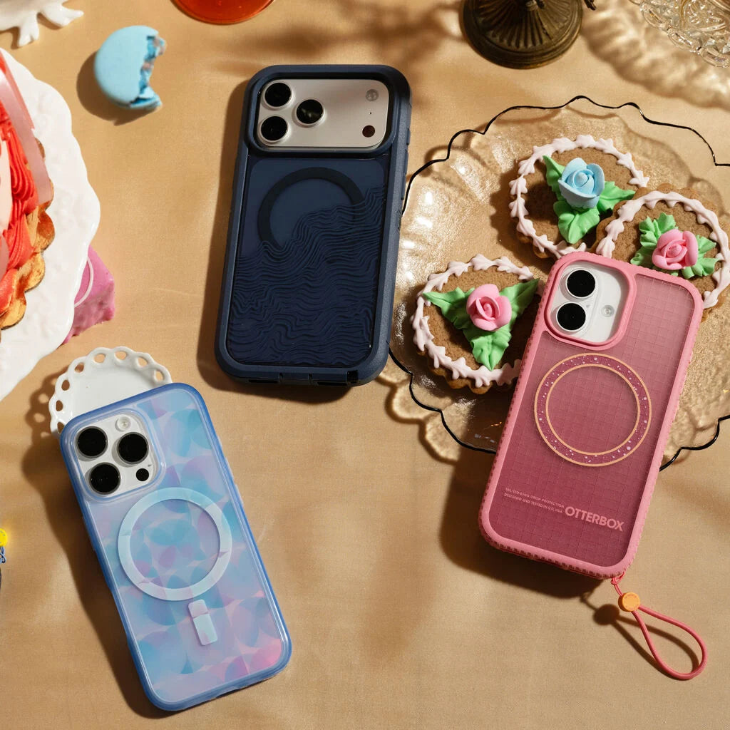 Four phone cases in different colors on a table with decorative items.