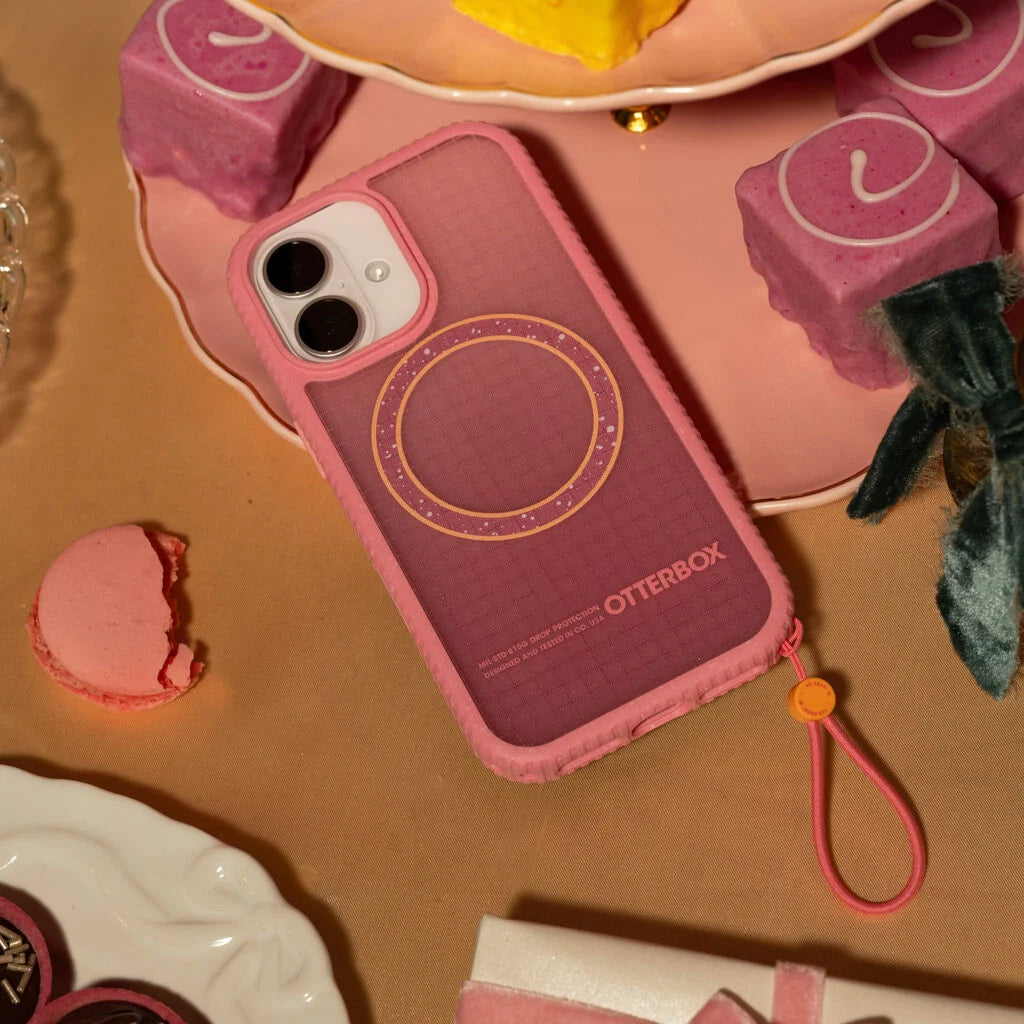 Pink OtterBox phone case on a decorative surface with small items