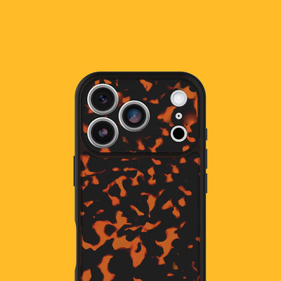 A close-up of a smartphone case with a black and orange tortoises pattern, shown on a solid yellow background.