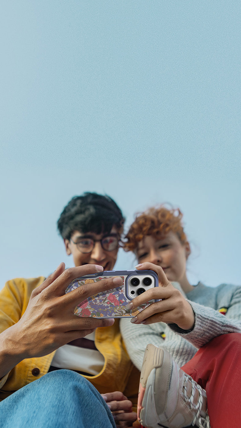 Two people taking a selfie with a phone against a clear blue sky.