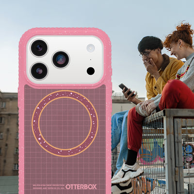 Pink Sole Series case on a silver iPhone 17 Pro. Background shows two people sitting on a bench.