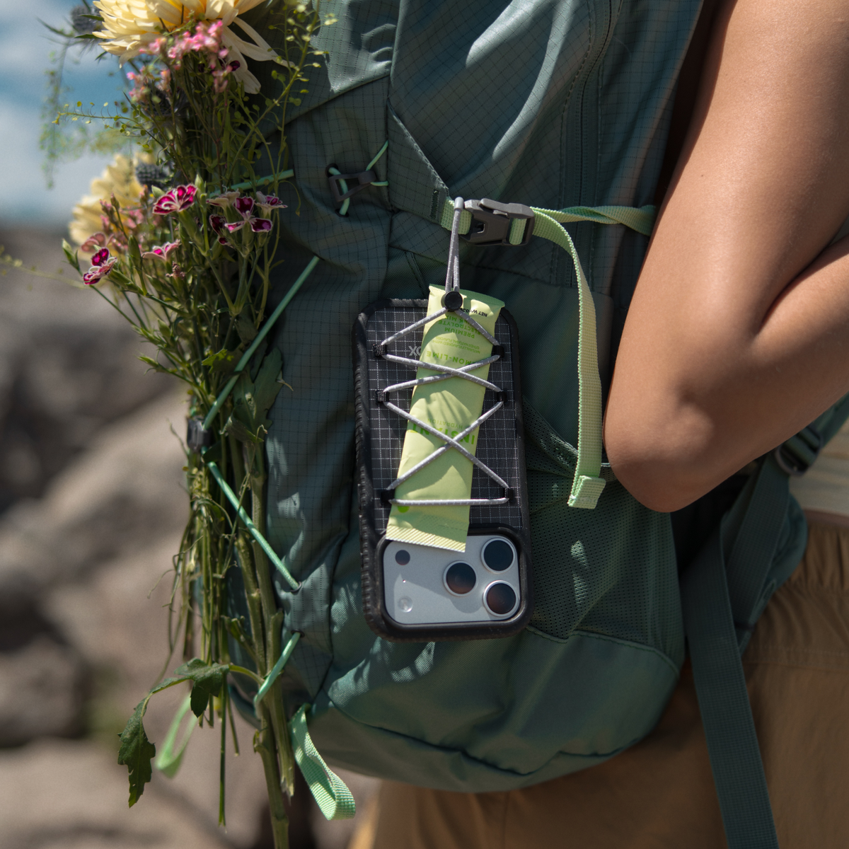 OtterBox Sole Series Pack phone case attached to a backpack with elastic cord storage, carrying small essentials during an outdoor adventure.