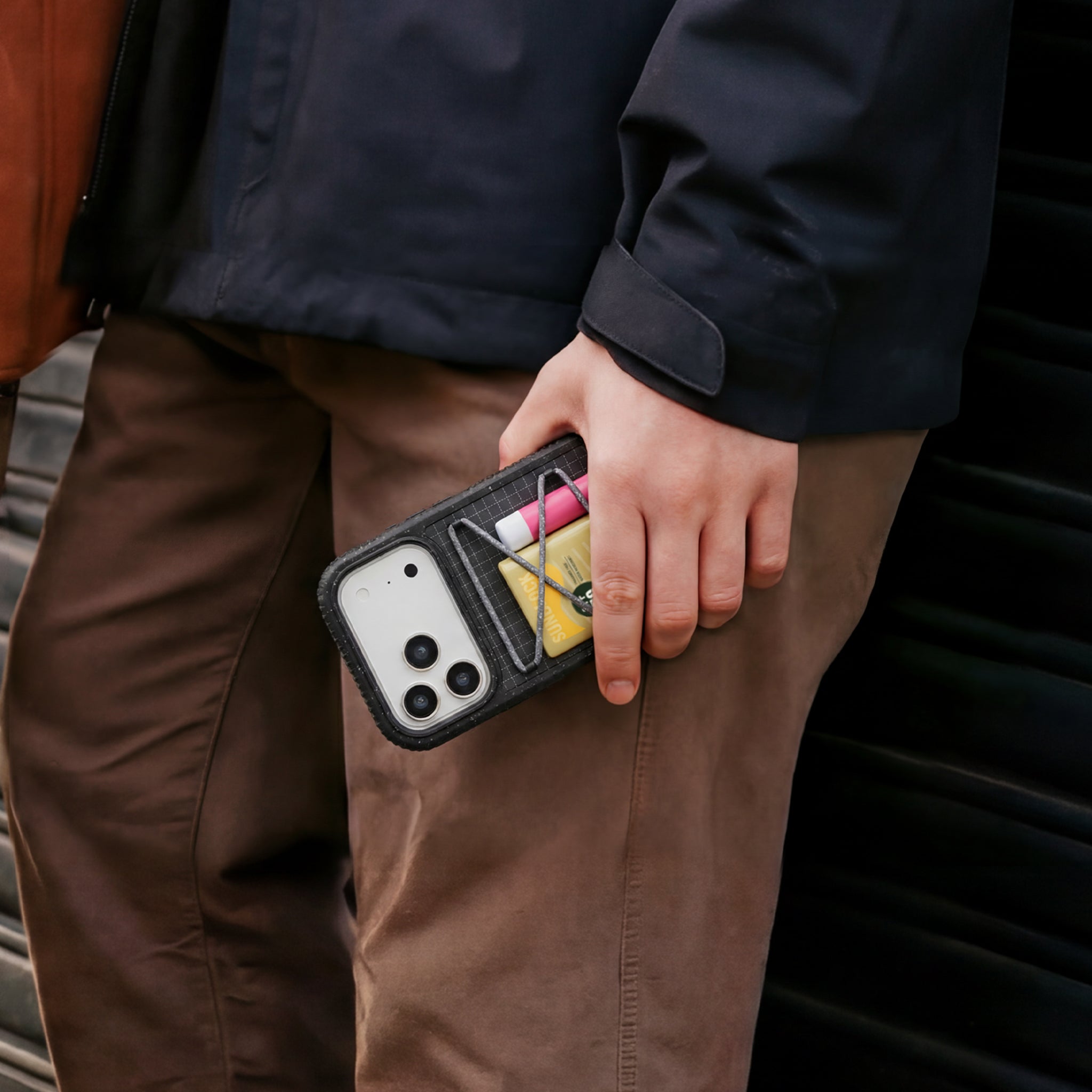 Person holding a phone case with tools in it, standing next to a car.