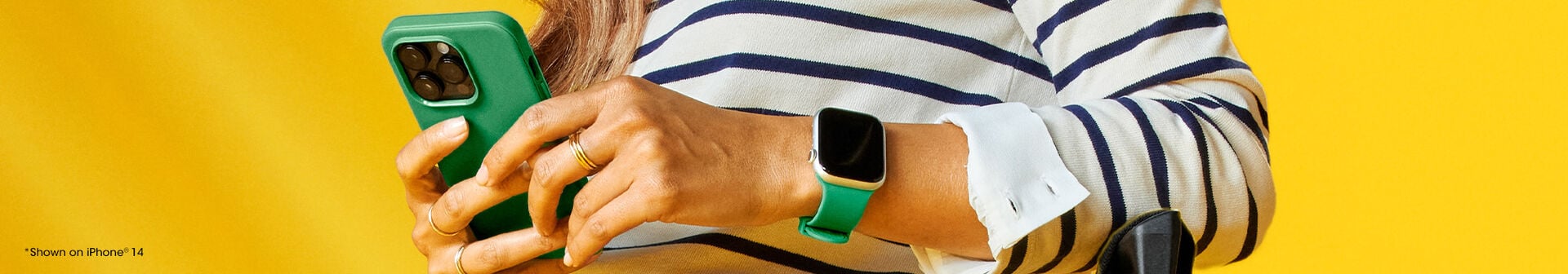 Woman holding an iPhone with a green phone case matching the green watch band on her Apple Watch she is wearing.