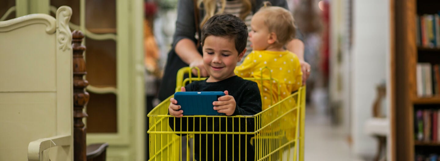 Toddler in shopping cart with OtterBox phone case